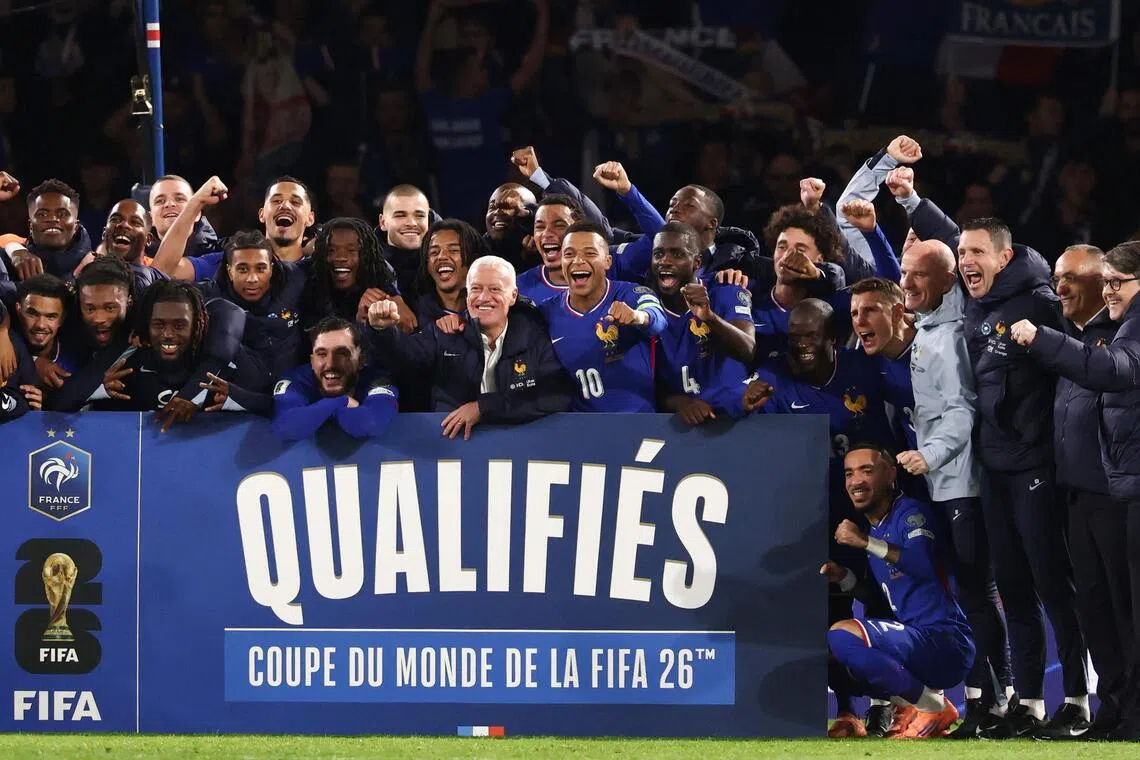 French forward Kylian Mbappe (wearing #10) together with head coach Didier Deschamps (to his right) and other players as they celebrate France's qualification for next year's World Cup.