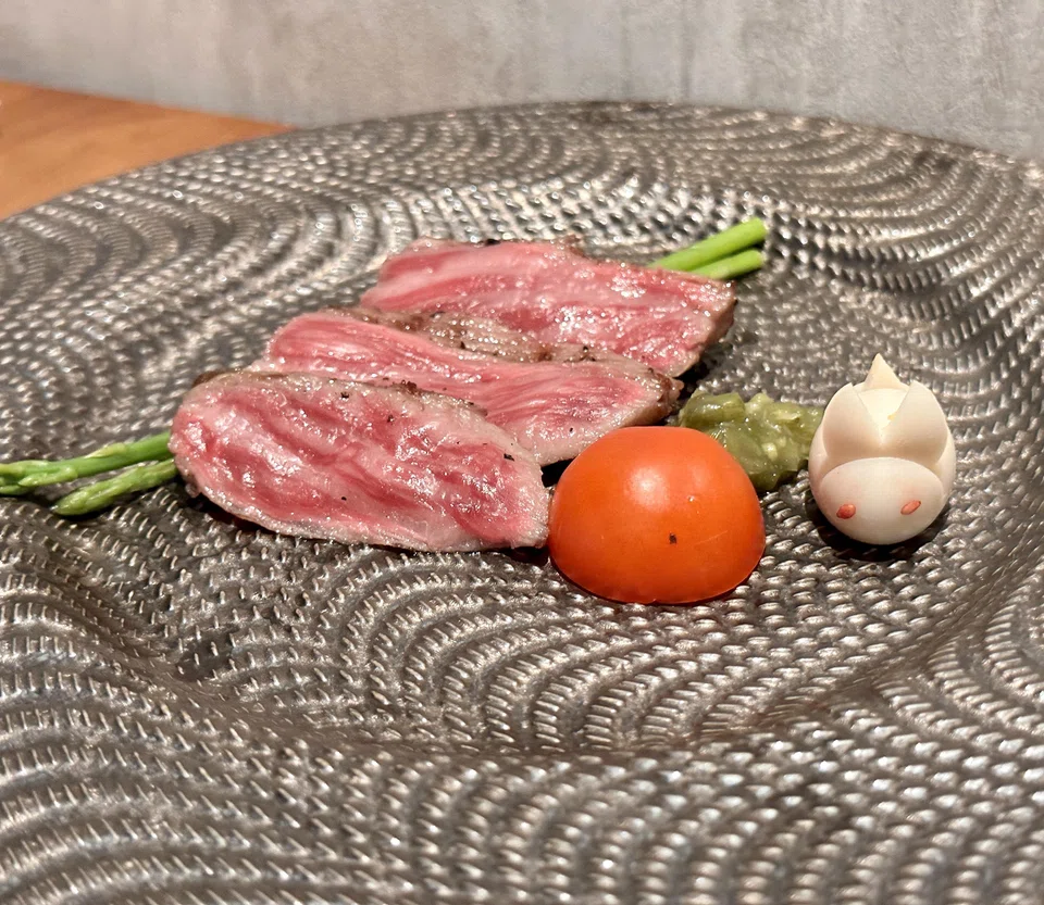 Slices of wagyu takaki are presented with a cute quail egg rabbit.