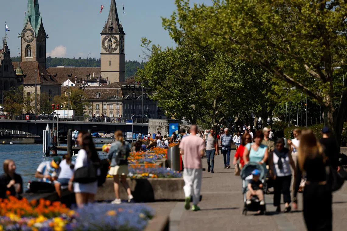 People walk along the shore of lake on a warm spring afternoon in Zurich, Switzerland April 30, 2025. REUTERS/Stefan Wermuth