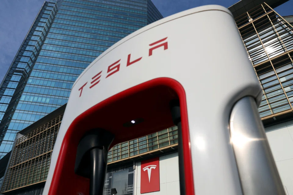 The Tesla logo is seen through a charging station outside a store of the electric vehicle (EV) maker in Beijing, China January 4, 2024. REUTERS/Florence Lo