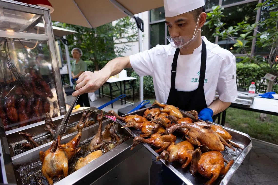 A chef fries pigeons in hot oil near Beiyuan Grand Hotel in Beijing, China, Aug 11, 2025. Beiyuan is among at least 15 high-end hotels nationwide hawking food outside in recent weeks, according to their social media and Chinese news sites.