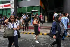 People gather on a street after evacuating a building in Manila on June 15, 2023, following a magnitude 6.2 earthquake struck the Philippines. 