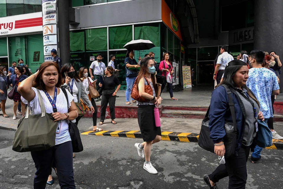 People gather on a street after evacuating a building in Manila on June 15, 2023, following a magnitude 6.2 earthquake struck the Philippines. 