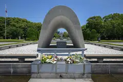 The Memorial Cenotaph at the Peace Memorial Park, with the Atomic Bomb Dome in the distance, in  Hiroshima, Japan.