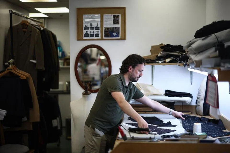 Apprentice tailor Charlie makes adjustments to a jacket at Henry Poole on Savile Row in London.