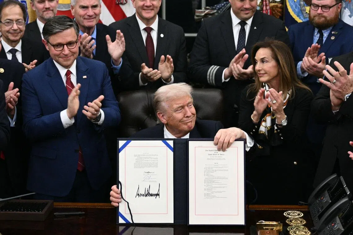 US President Donald Trump (centre) shows the signed bill package to re-open the federal government as the Speaker of the House Mike Johnson (left) and other Republican leaders applaud in the Oval Office of the White House in Washington, DC, Nov 12, 2025. 