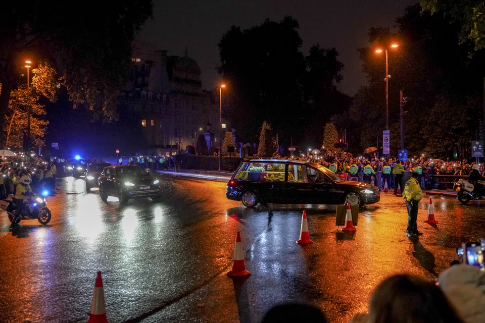 A hearse carrying the coffin of Queen Elizabeth II passes throngs of people on its way into Buckingham Palace in London, England on Sept 13, 2022. 