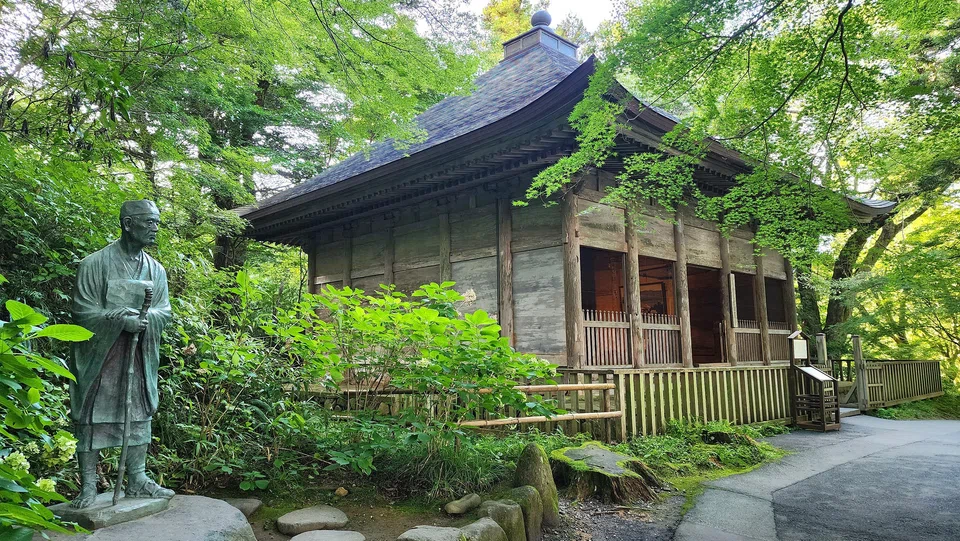 A statue of poet Matsuo Basho stands beside the former outer shell of Konjiki-do, the Golden Hall, at Chuson-ji temple. 