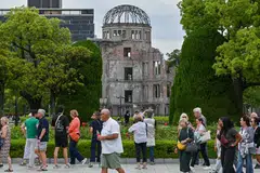 Tourists in the Peace Memorial Park in Hiroshima, with the Atomic Bomb Dome – the only structure that remained standing in the area around the US' atomic bombing of the city on Aug 6, 1945 – in the background. 