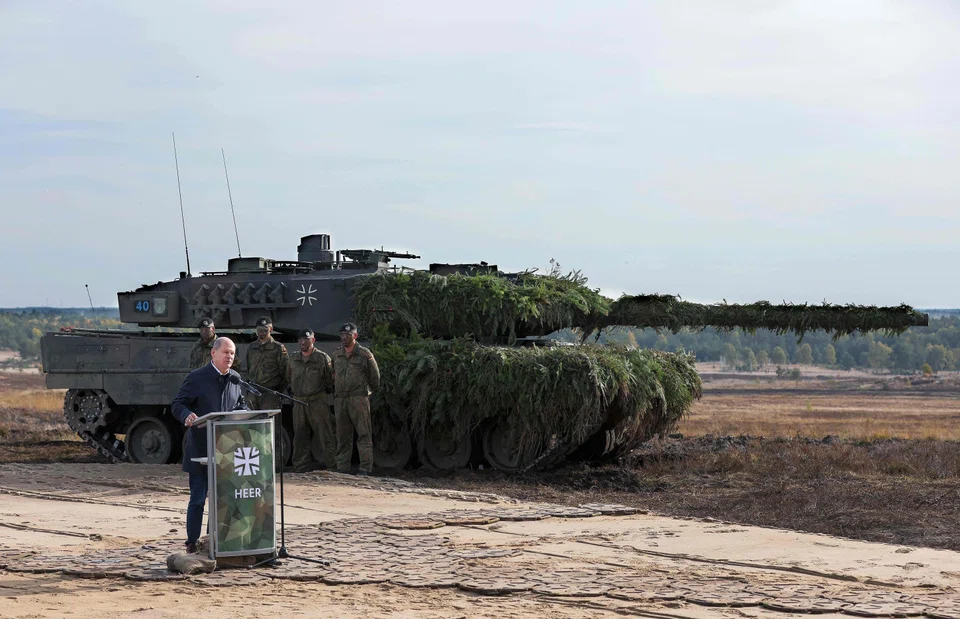 German Chancellor Olaf Scholz speaks next to a Leopard 2 battle tank of the German armed forces Bundeswehr as he visits troops on a training exercise at the military ground in Ostenholz, northern Germany, on Oct 17, 2022. 