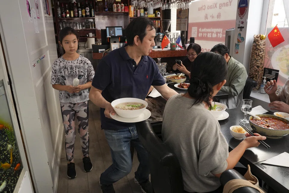 Tang Zhongqiu serves meals at Yang Xiao Chu, his petite Chinese restaurant near the table tennis venue in the 15th arrondissement of Paris, which has become an unofficial clubhouse for athletes, team officials and fans alike, on Aug. 3, 2024. "I just look after them as if they were my family members," Tang said of the Olympic athletes, many of whom are celebrities back home in China. (Weiyi Cai/The New York Times) 

