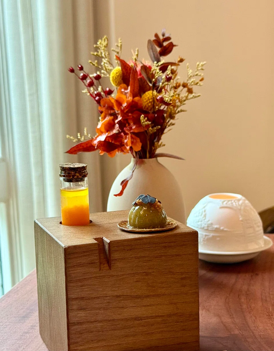 Canapes of apple-celery ball and pumpkin-argousier juice, with a Bernardaud tea light in the background.