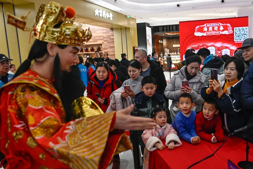A life-size humanoid robot dressed as China’s traditional wealth god says to a visitor: “I hope that in the new year, you can also eat healthily and deliciously, and be happy every day.”