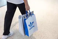 A commuter holds an Adidas shopping bag while walking through the Lusail metro station in Doha, Qatar.