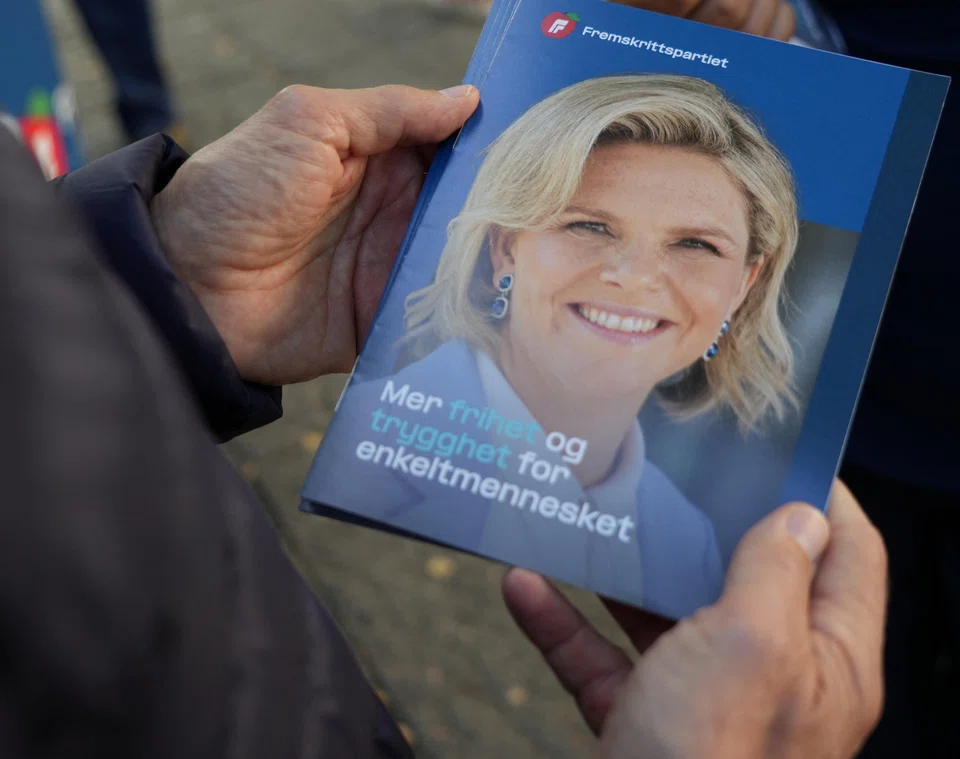 A supporter of the Progress Party holds a leaflet showing party leader Sylvi Listhaug, who says "Norway should be the last country in the world to stop (oil) production".