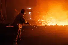 A worker stands by a stream of molten steel as smoke engulfs a chamber at a steel factory in Huai’an, China, July 22, 2025. Excess production and exports by Chinese steelmakers have become an international concern.