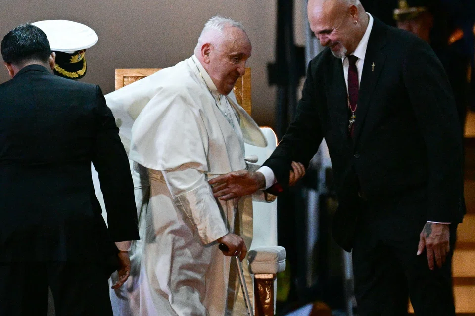 Pope Francis is helped by Papua New Guinea's Deputy Prime Minister John Rosso (R) as he takes part in a welcome ceremony upon arrival at the Port Moresby International airport on Sep 6, 2024. The pope is on the second stop of a marathon 12-day tour to the Asia-Pacific region. 