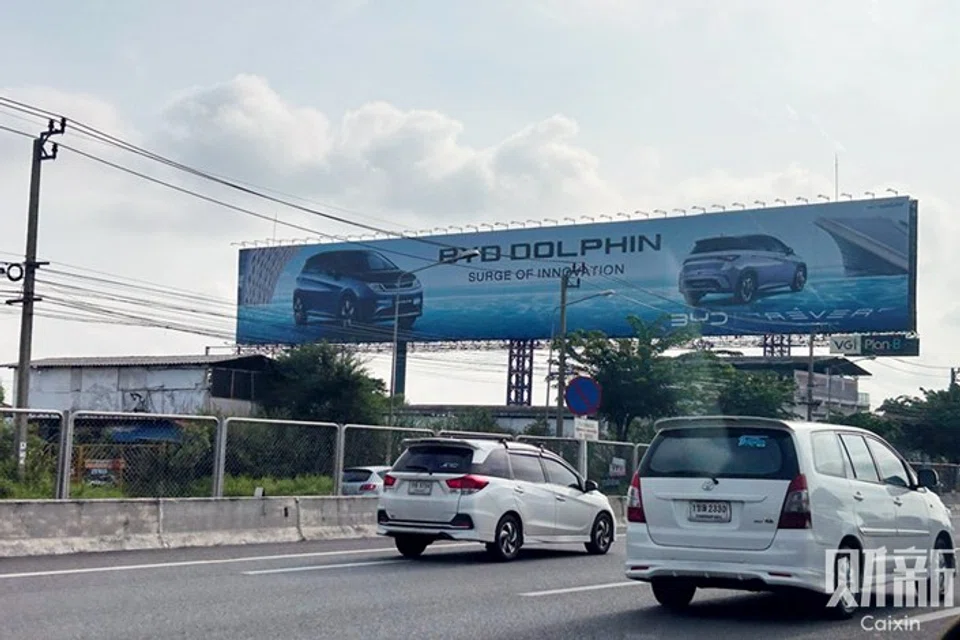 A billboard displays an advertisement for a BYD Dolphin car along a highway from downtown Bangkok to Suvarnabhumi International Airport.