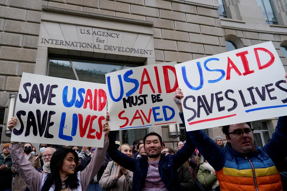 Protestors hold placards as the USAID building sits closed to employees after a memo was issued advising agency personnel to work remotely, in Washington, D.C., Feb 3, 2025. 