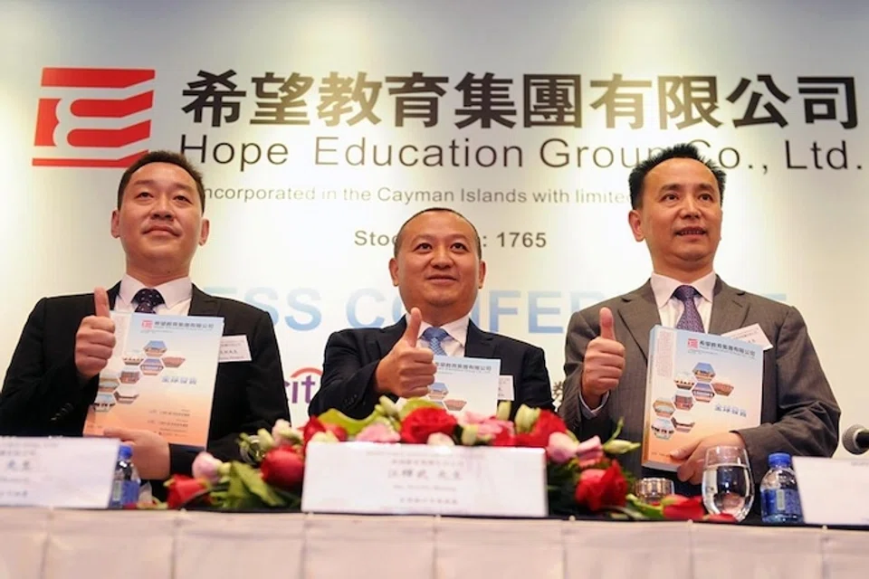 (Centre) XJ International President Wang Huiwu attends a press conference in Hong Kong on July 23, 2018.  XJ International Holdings, who used to be called Hope Education Group, said in a filing last month that it had defaulted on the US$315 million of convertible bonds.