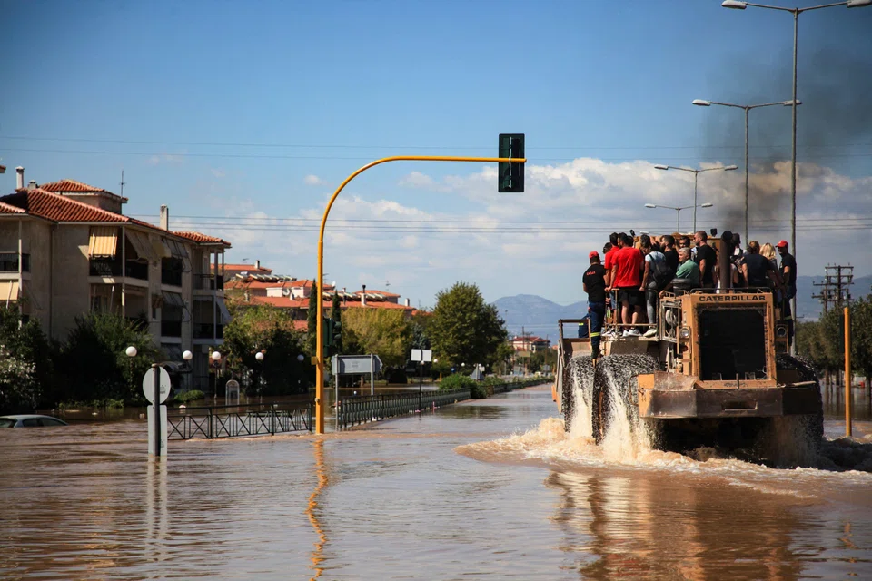 People are evacuated by an excavator from a flooded area in Larissa, central Greece. Climate change can disrupt business operations, evaporate demand, impose obsolescence and shrink market share.