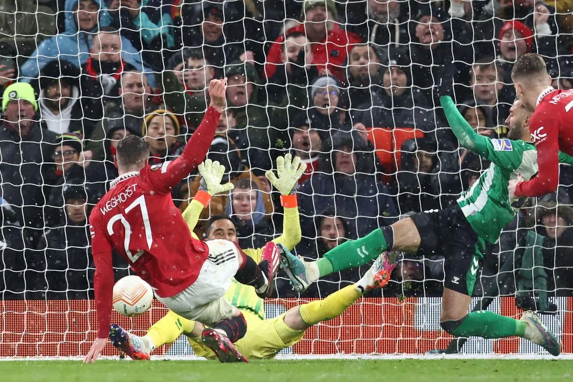 Manchester United's Dutch striker Wout Weghorst (L) scores their fourth goal during the UEFA Europa league round of 16 first leg football match between Manchester United and Real Betis at Old Trafford stadium in Manchester, north-west England, on March 9, 2023. (Photo by DARREN STAPLES / AFP)