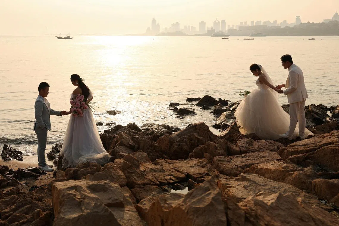 Couples take part in wedding photoshoots by the sea in Qingdao, Shandong province, China, April 21, 2024. More than 6.1 million couples registered for marriage last year, down from 7.68 million a year earlier, figures from the Ministry of Civil Affairs showed. 