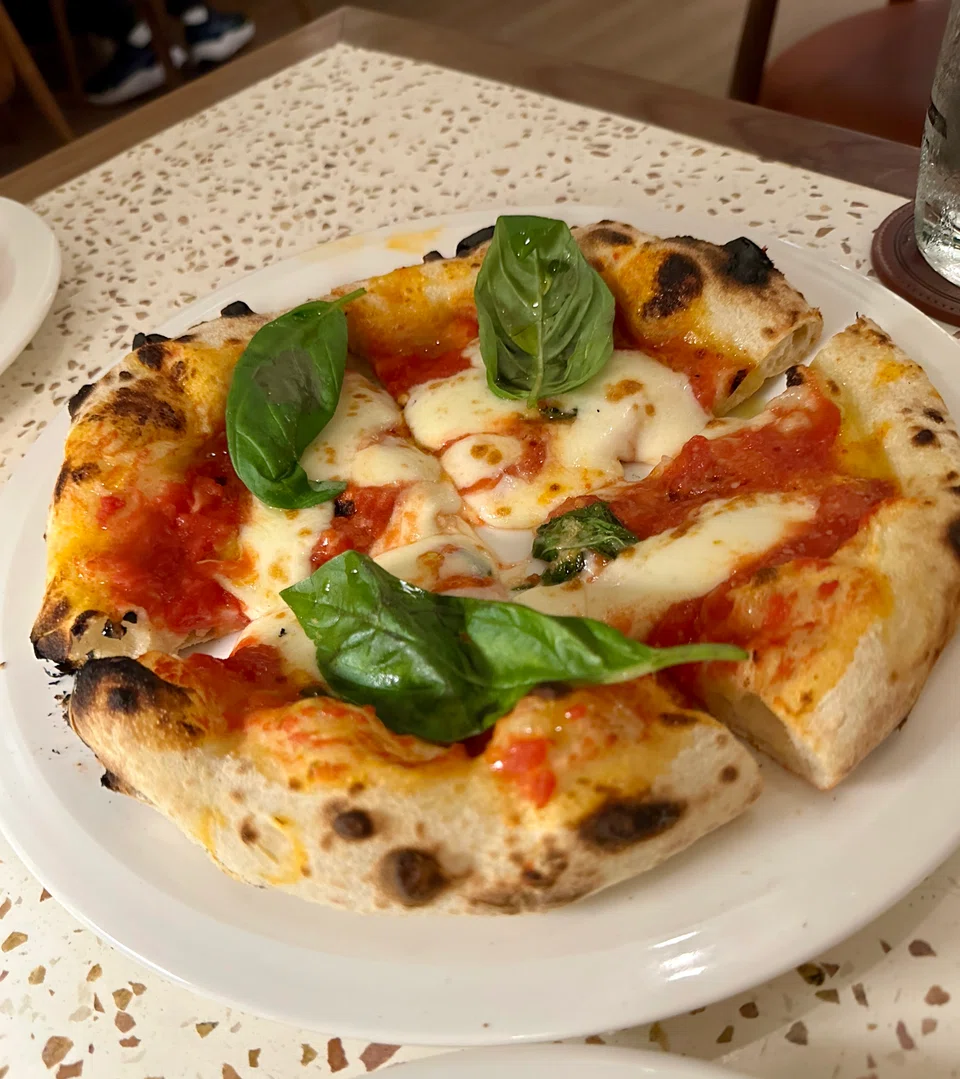 Margherita pizza features bouncy dough covered with tomato sauce and fior di latte cheese.