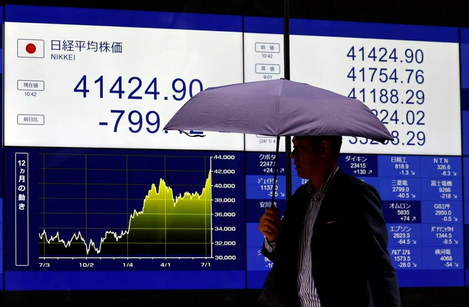 A man walks past an electric screen displaying Japan's Nikkei share average in Tokyo, Japan, July 12, 2024. The yen spiked from around 161.50 per dollar to as strong as 157.44, fuelling talk that officials had intervened again, having done so in April when the yen hit a 38-year low.  