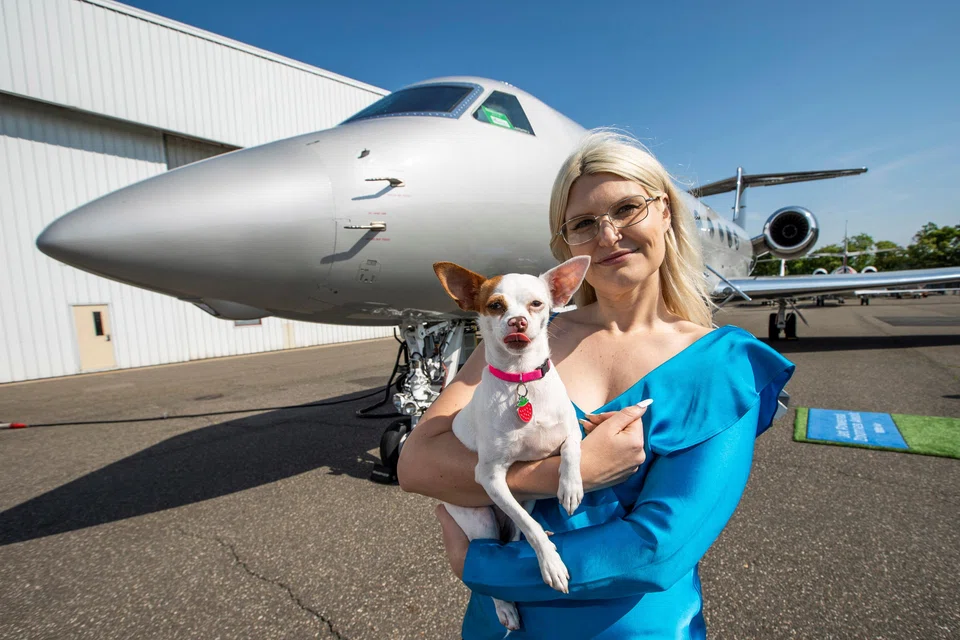 A woman poses with a dog during a press event introducing Bark Air, an airline for dogs, at Republic Airport in East Farmingdale, New York, May 21, 2024.