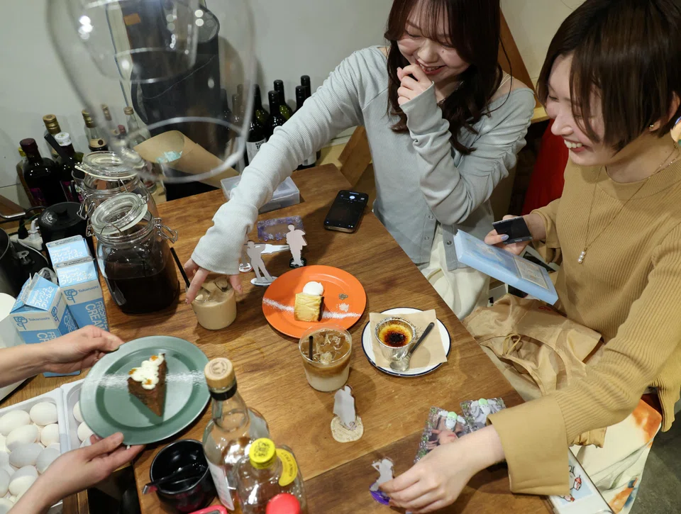 Momoka Matsui and her co-worker Saki Matsumoto prepare to take photos of acrylic stand figure models of their favourite idols with cakes and teas, which they ordered at After All Coffee, where Matsui’s favourite boy band stopped by, Tokyo, Japan, March 23, 2025.