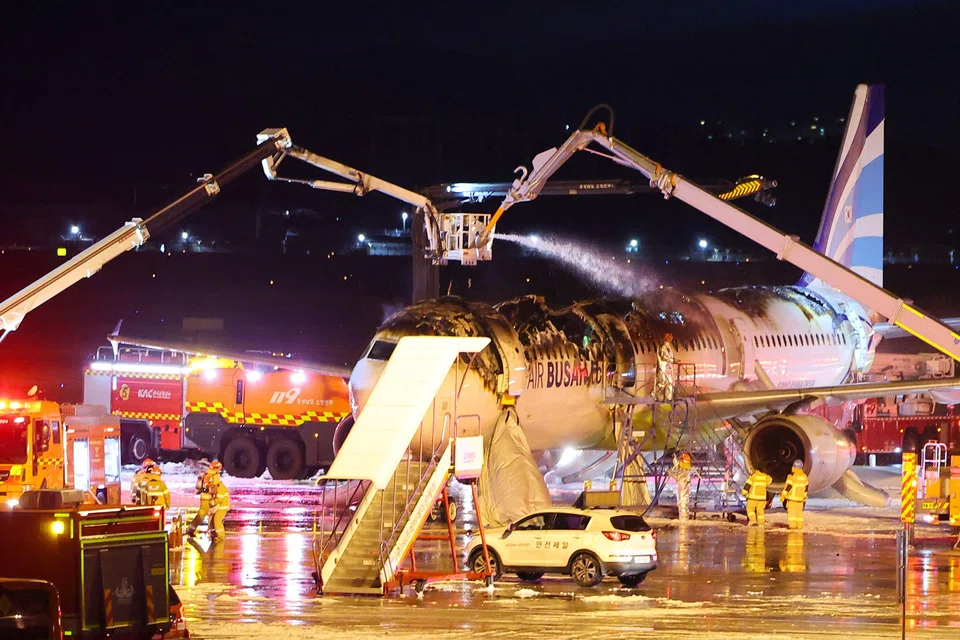Firefighters work to extinguish a fire that broke out on an Air Busan passenger plane bound for Hong Kong, at Gimhae International Airport in Busan, South Korea, Jan 28, 2025. 