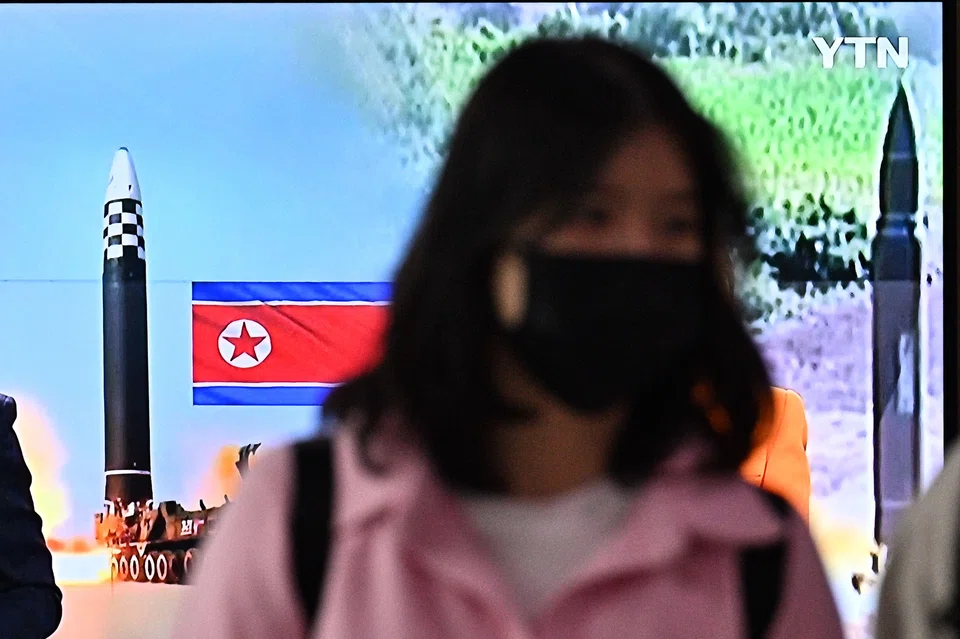A woman walks past a television report showing a news broadcast  of a North Korean missile test at a railway station in Seoul on Oct 6, 2022. 
