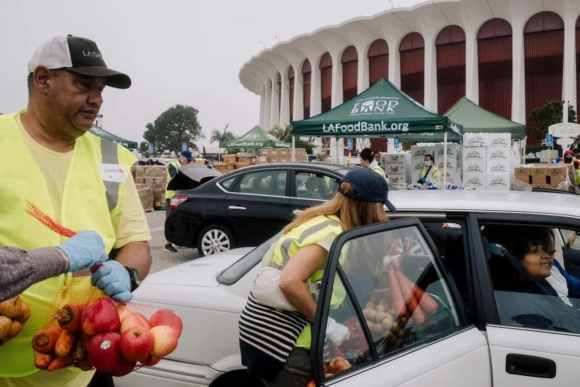 Volunteers load donated food items into a resident's vehicle during a food bank distribution at The Kia Forum in Inglewood, California, Nov 1, 2025. 