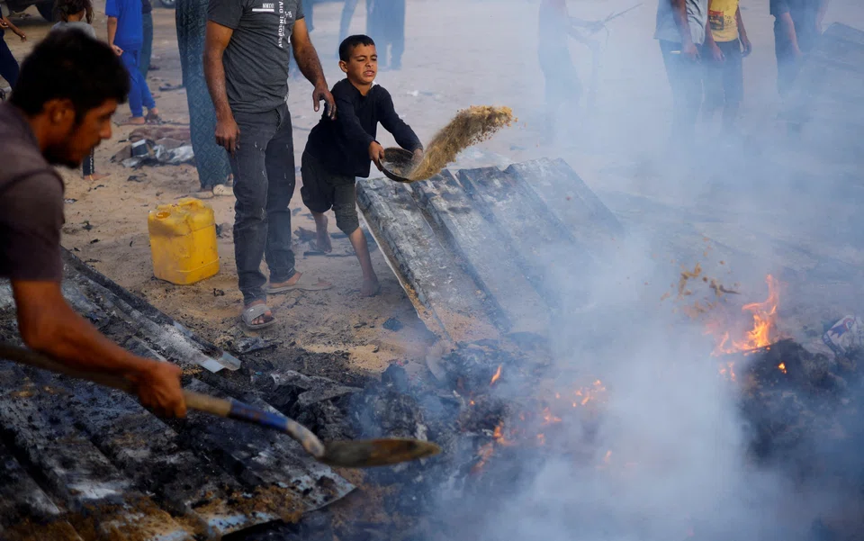 Palestinians put out a fire at the site of an Israeli strike on an area designated for displaced people, in Rafah, in the southern Gaza Strip, May 27, 2024.