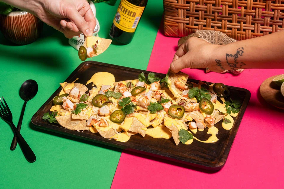 Nachos Chilangos are addictive corn chips in a cheesy sauce with grilled shrimp.