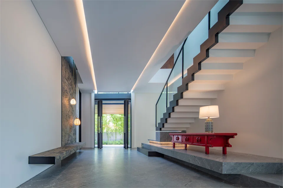 A floating staircase, perched on a raised platform, adds a sense of lightness and airiness to the entrance foyer.
