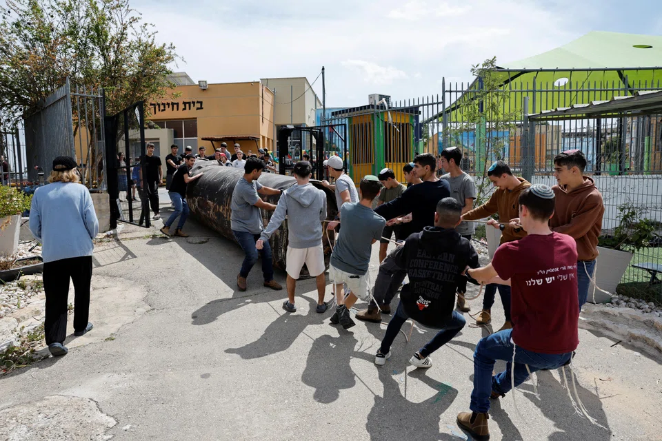 Teenagers dragging a part of a missile that landed in the playground of a school on Sunday night in the Israeli settlement of Peduel located in the occupied West Bank.