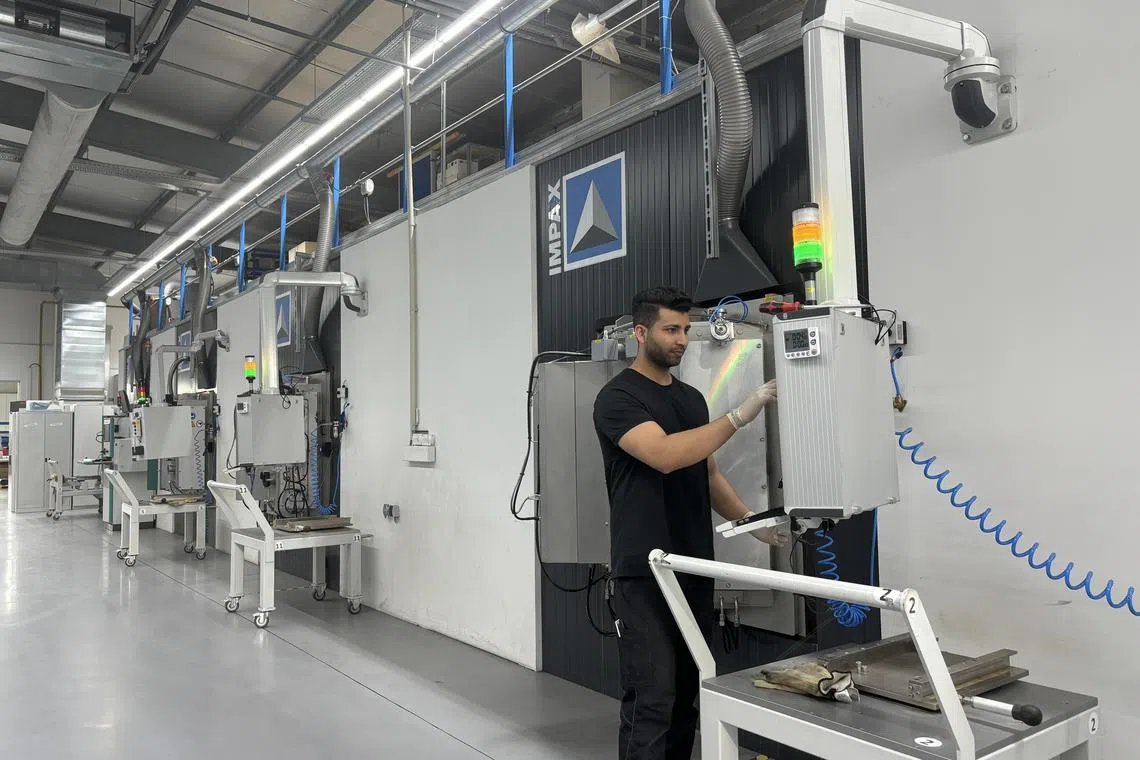 A staff member works on the coating machine at AxynTec's facility in Germany. AxynTec was acquired by Nanofilm. For the full year, Nanofilm's revenue stood at S$204.3 million. 