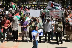 A pro-Israel counter-protester walks with an Israeli flag near protesters attending a demonstration in support of Palestinians in Gaza, at UCLA in Los Angeles, California, April 28, 2024. Israel’s government has come under intense pressure from global allies to reach a ceasefire in the war that humanitarians say has brought Gaza to the brink of famine. 