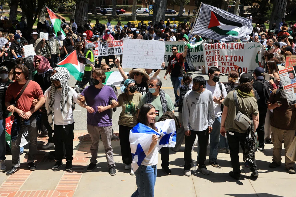 A pro-Israel counter-protester walks with an Israeli flag near protesters attending a demonstration in support of Palestinians in Gaza, at UCLA in Los Angeles, California, April 28, 2024. Israel’s government has come under intense pressure from global allies to reach a ceasefire in the war that humanitarians say has brought Gaza to the brink of famine. 