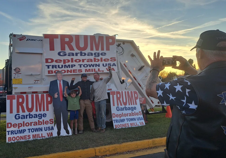 A garbage truck parked at the entrance is a hit among Trump supporters at the rally with many posing for photos by it.