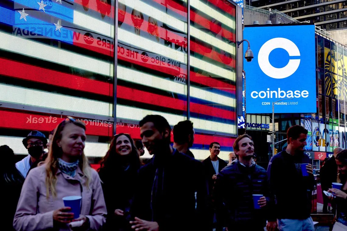 FILE — Coinbase employees gather in Times Square to see the launch of the company’s initial public offering displayed on the Nasdaq tower, April 14, 2021. Crypto companies are laying off staff, freezing withdrawals and trying to stem losses, raising questions about the health of the ecosystem. (Gabby Jones/The New York Times)