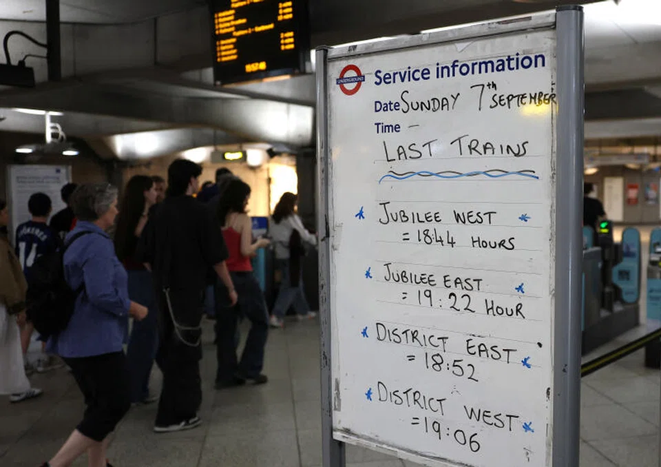 Travellers walk past a passenger information sign ahead of planned tube rail strikes, at Westminster Underground Station in London.