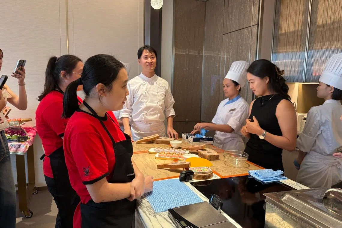 Metta School alumni Shirley Heng (left) and Rachel Tan (second from left) are joined by professional golfer Minjee Lee (in black) to learn how to make kueh from MBS chef Hoi Kuok I (centre, in white).