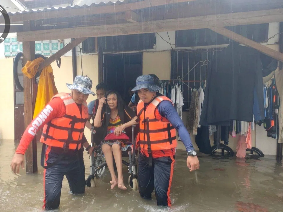 Coast guard personnel evacuating a resident from a flooded house in Plaridel, Misamis Occidental province, Philippines, Dec 26, 2022. 