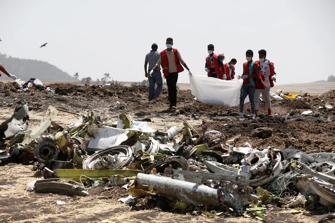 Ethiopian Red Cross workers carry a body bag with the remains of Ethiopian Airlines Flight ET 302 plane crash victims near the town of Bishoftu, south-east of Addis Ababa, Ethiopia, Mar 12, 2019. 
