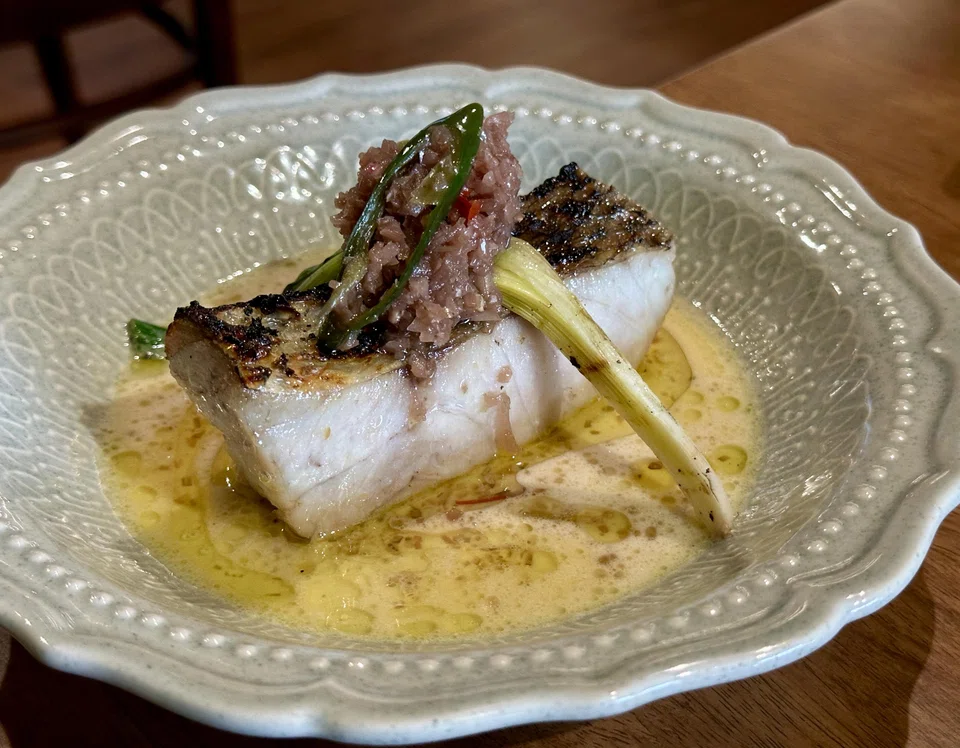 A fat slice of well-cooked threadfin fillet sits in a savoury spiced coconut broth.
