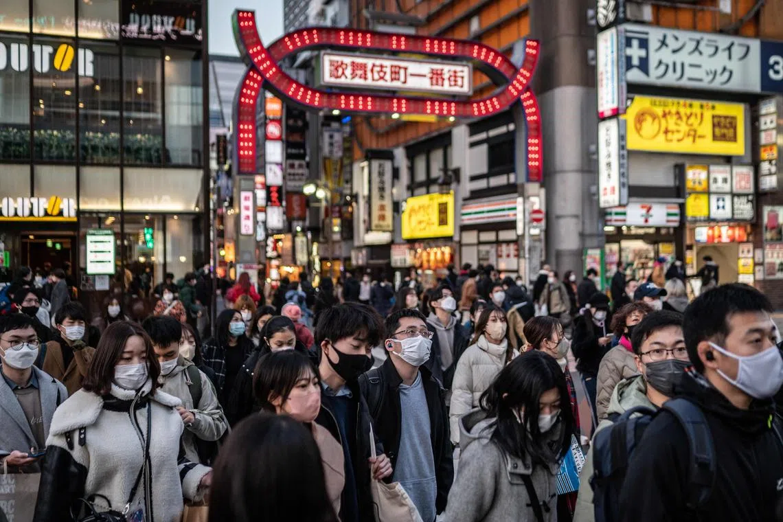Pedestrians cross a street in Tokyo's Shinjuku area on February 5, 2023. (Photo by Yuichi YAMAZAKI / AFP)