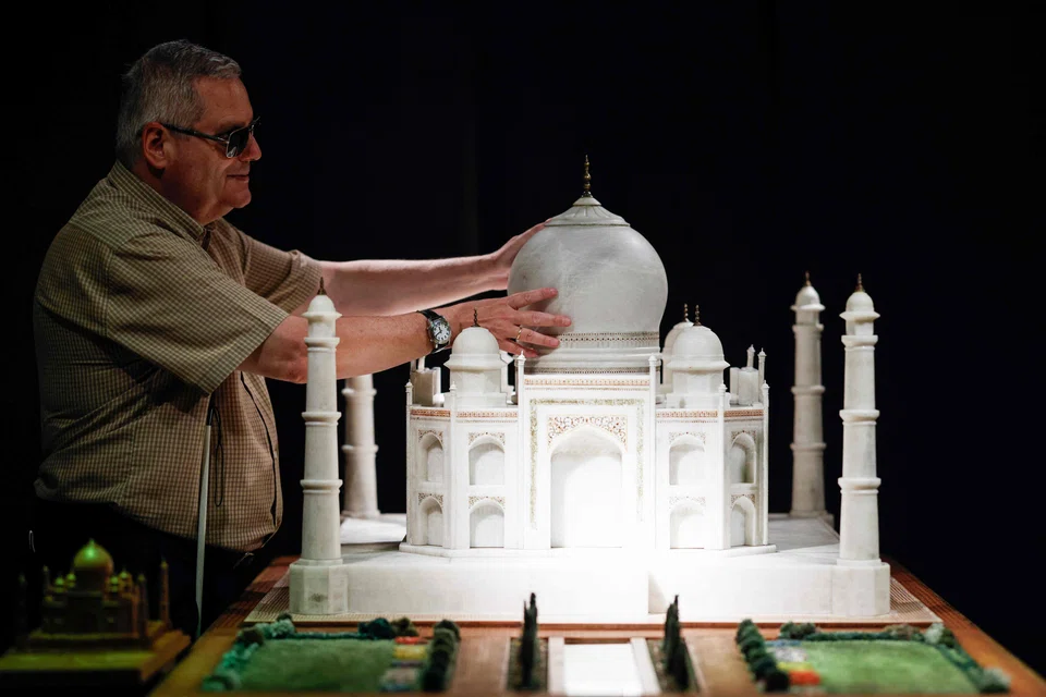 Visually impaired Jose Pedro Gonzalez touches the model of the Taj Mahal with his hands.